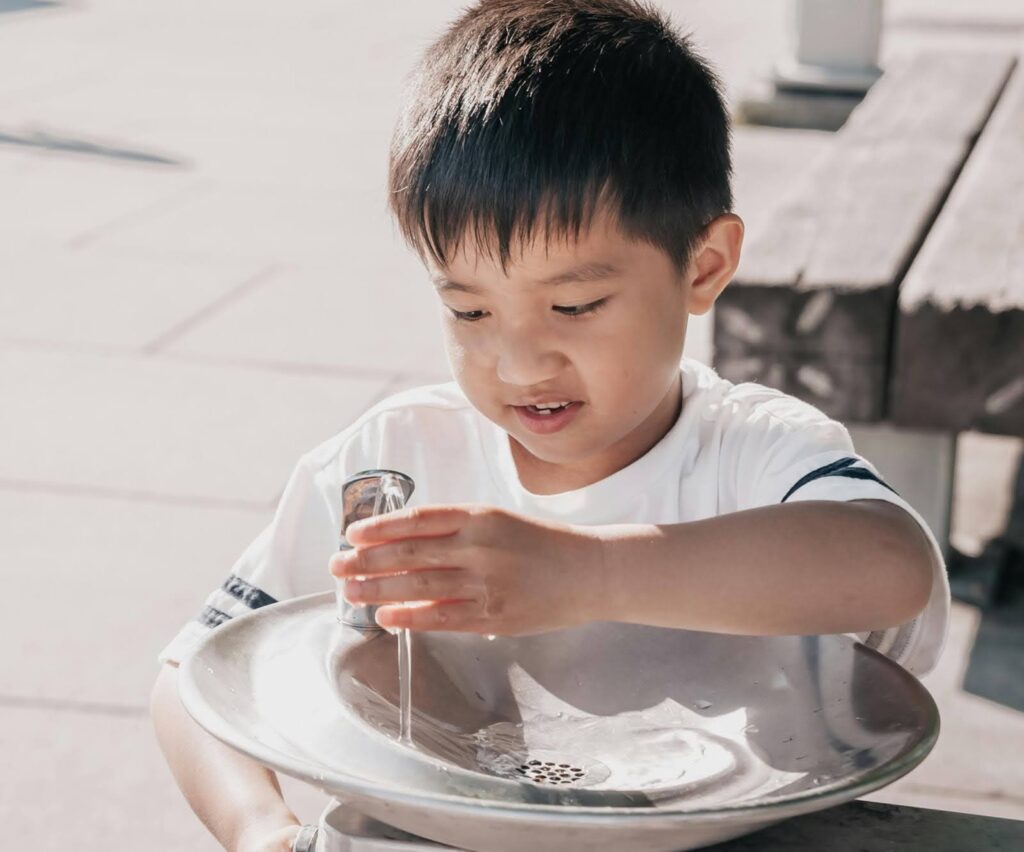 a little boy using a water fountain to get a drink